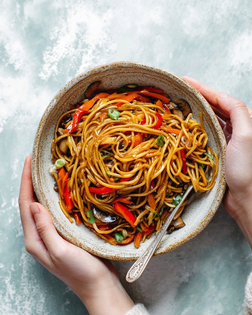 A pair of woman's hands hold a rustic ceramic bowl filled with stir-fried noodles. The dish has a base layer of glossy, golden-brown noodles twisted in a circular shape. Mixed within are thin strips of bright orange carrots and red bell peppers, scattered green onion slices, and light brown, soft-textured mushroom pieces. A silver fork rests in the top right part of the bowl, partially wrapped with noodles. The background shows a white marbled texture. photo taken with an iphone --ar 4:5 --v 7