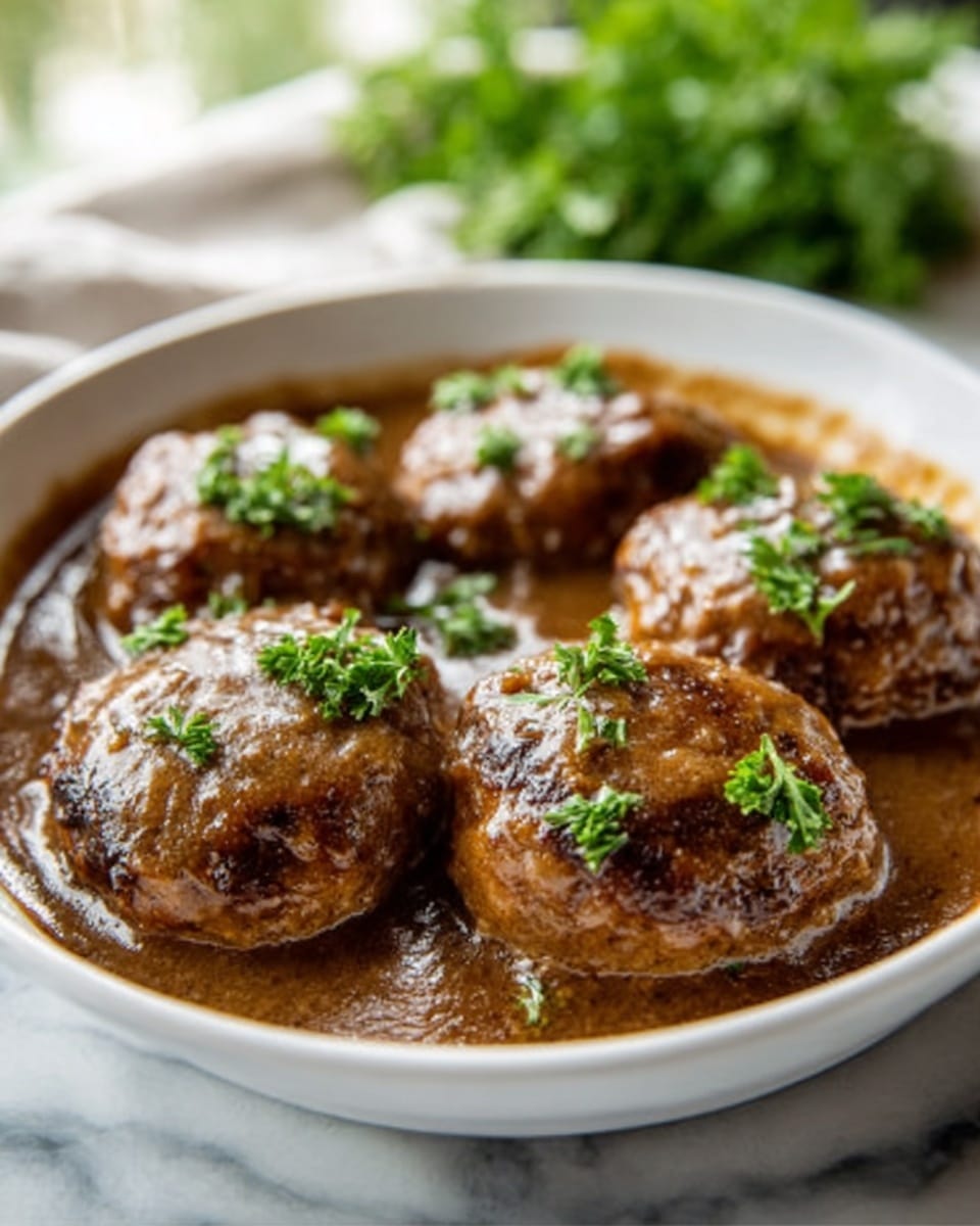 The image shows a white bowl filled with five round meat patties covered in a thick brown sauce. The patties have a slightly rough texture, and the sauce looks smooth and shiny over them. Small fresh green parsley leaves are sprinkled on top of the patties, adding a bright contrast to the brown sauce. The bowl sits on a white marbled surface with some blurred green plants in the background. The photo taken with an iphone --ar 4:5 --v 7