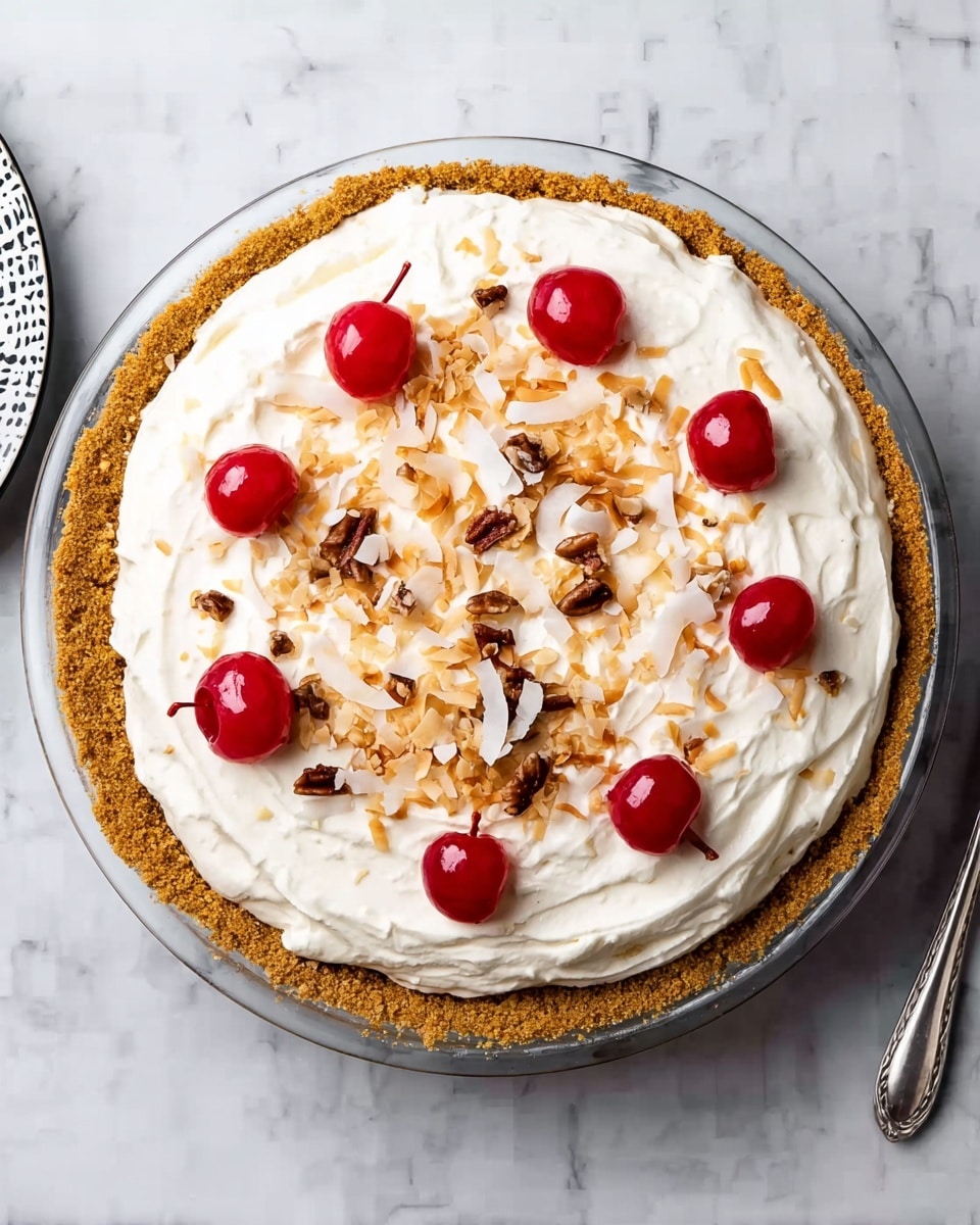 This image shows a pie with three main layers. The bottom layer is a golden brown, crumbly crust that looks thick and firm, forming a round base. On top of the crust is a thick layer of creamy white filling, spread evenly but with some soft swirls and small chunks visible inside it. The top layer has a decoration made of several bright red cherry halves placed evenly around the edge. In the middle, there are small brown nut pieces and some golden toasted coconut flakes scattered on the creamy surface. The pie is on a clear glass plate, placed over a white marbled surface. Photo taken with an iphone --ar 4:5 --v 7
