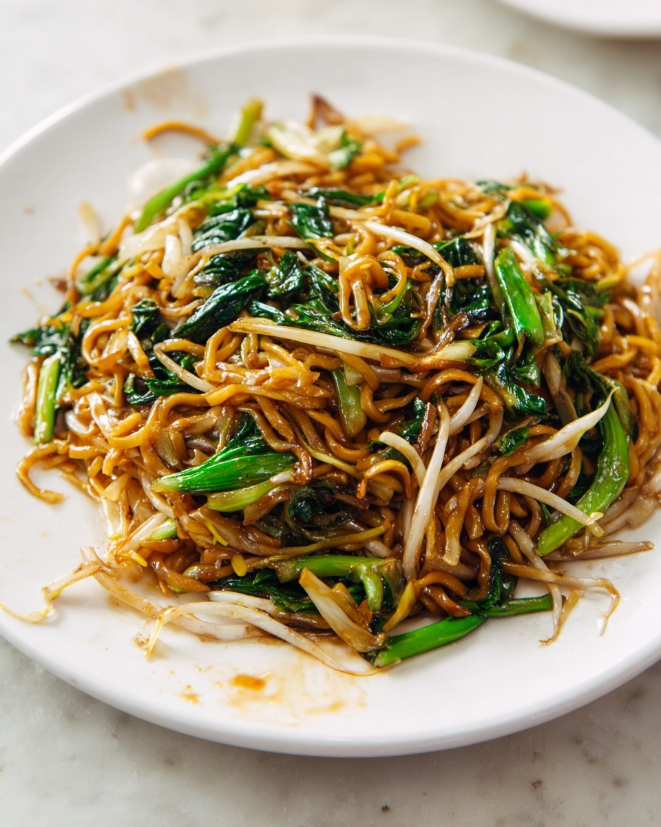 A white plate holds a single pile of stir-fried noodles in the center. The noodles are glossy and light brown, mixed with bright green leafy vegetables and some light beige bean sprouts. The sauce adds a shiny texture, and the noodles are intertwined with the vegetables evenly spread. The plate rests on a white marbled surface, and there is a slight sauce stain near the food. Photo taken with an iphone --ar 4:5 --v 7