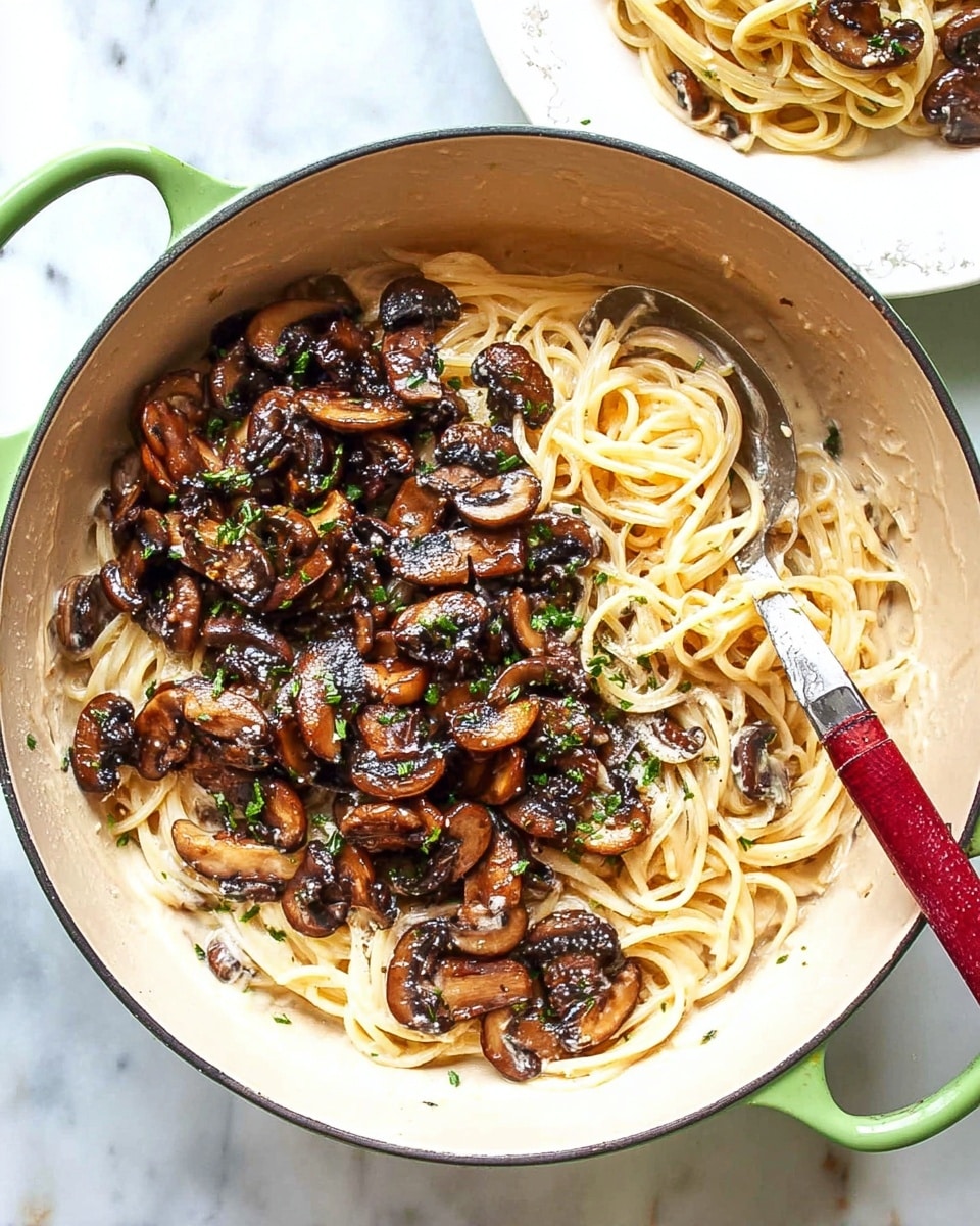 A white shallow bowl holds a creamy pasta dish with long spaghetti noodles fully coated in a light beige sauce. On top, there are many cooked mushrooms in different brown shades, some sliced and some whole, scattered evenly. Fresh green herbs are sprinkled throughout, adding small bright green spots on the pasta. A woman's hand is holding a black spoon in the bowl, lifting some pasta from the middle. The bowl is placed on a white marbled surface. photo taken with an iphone --ar 4:5 --v 7