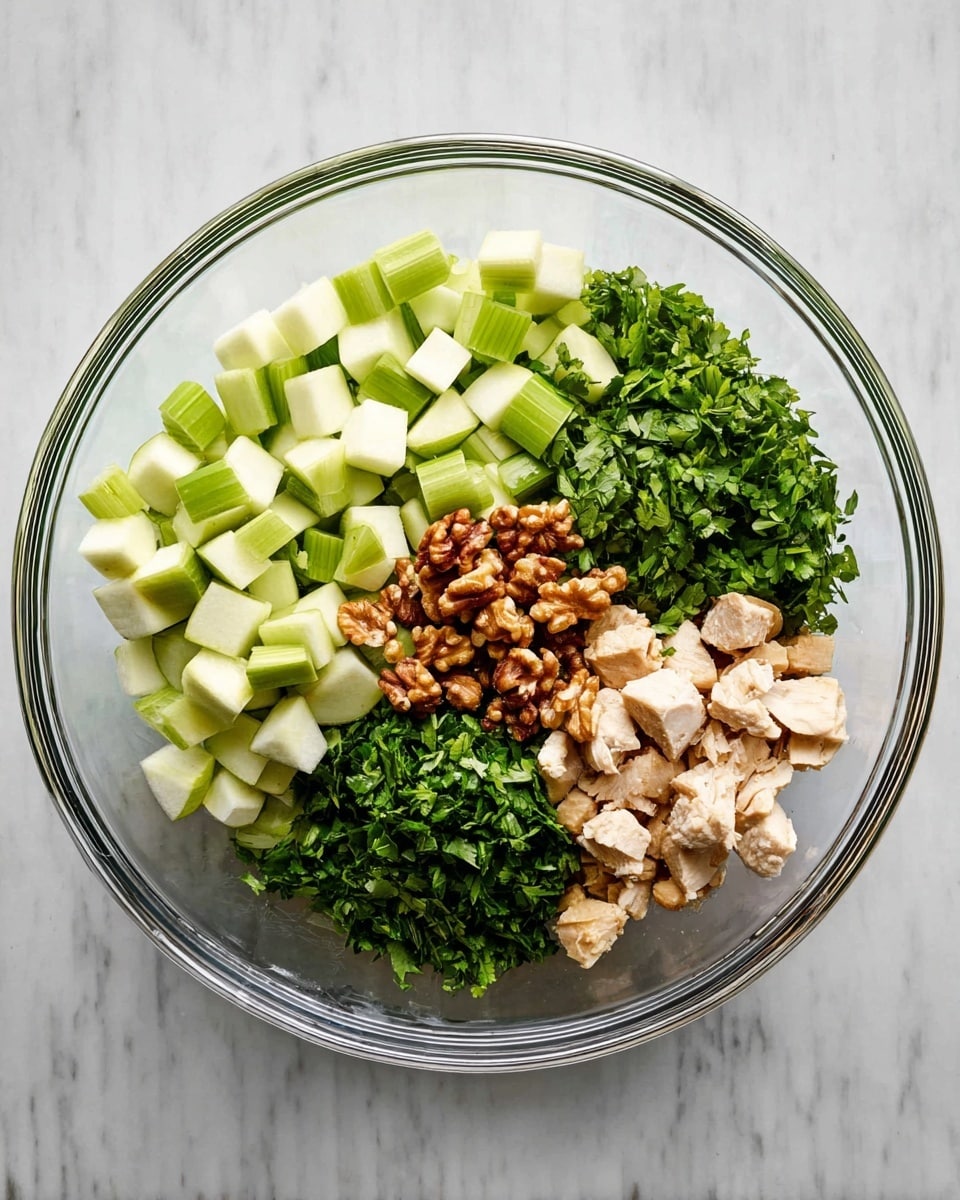 The image shows a clear glass bowl placed on a white marbled surface, filled with five separate layers of ingredients arranged in neat sections. There are small green celery pieces on the left side, pale green diced apples on the upper right, roughly chopped dark green parsley in the middle right, small pieces of cooked light beige chicken at the bottom right, and a small pile of brown walnuts in the center. Each ingredient maintains its color and texture clearly, creating a vibrant, fresh look. Photo taken with an iphone --ar 4:5 --v 7