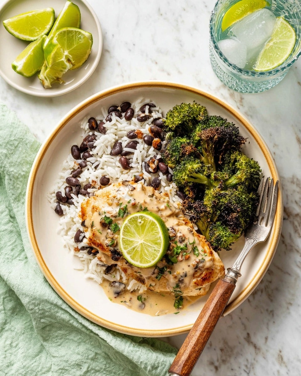 The dish shows a white plate with a beige rim placed on a white marbled surface, holding three main layers: on the left, a piece of light golden cooked chicken topped with a creamy sauce mixed with herbs and spices, garnished with a fresh green lime slice on top; beside the chicken, there is white rice mixed with black beans giving a mix of white and dark colors; on the right side of the plate, there is green roasted broccoli with some charred dark edges. A fork with a wooden handle rests on a light green cloth napkin next to the plate. In the upper left corner, there is a small white plate with green lime wedges, and in the upper right, there is a glass with ice and water. Photo taken with an iphone --ar 4:5 --v 7