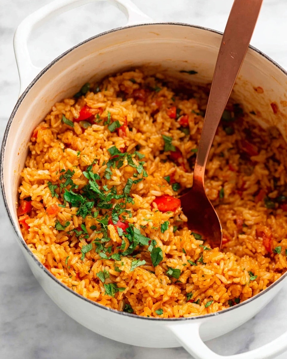 A white pot filled with cooked orange rice mixed with small pieces of red bell pepper and onions, garnished with chopped green cilantro leaves scattered on top. A copper-colored spoon is dipped into the rice on one side of the pot. The pot is placed on a white marbled surface. photo taken with an iphone --ar 4:5 --v 7