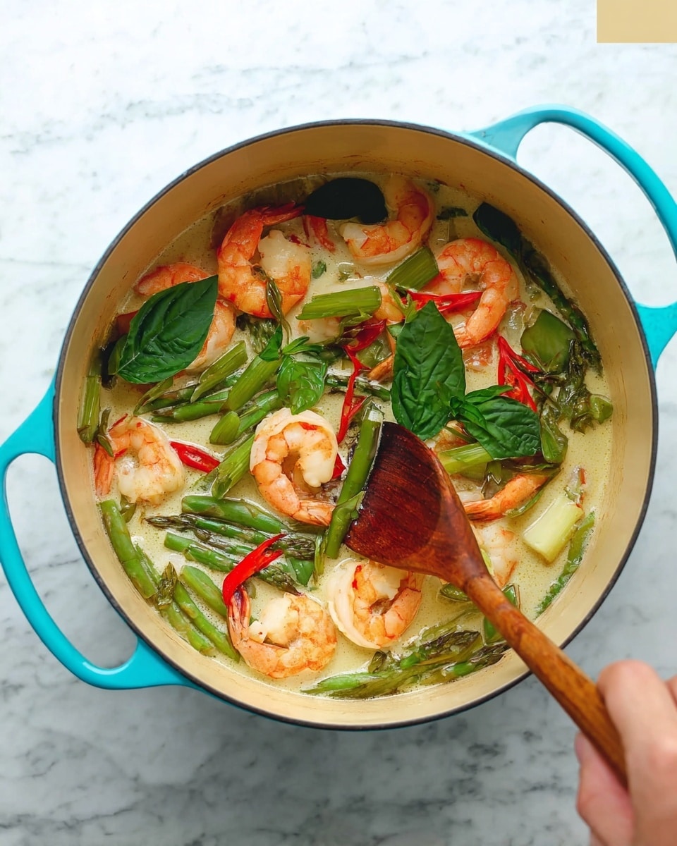 A light blue cooking pot filled with a creamy sauce containing several orange-pink shrimp, bright green basil leaves scattered on top, and pieces of green asparagus and red chili peppers mixed inside. A woman's hand is holding a wooden spoon stirring the ingredients in the pot. The pot is placed on a white marbled surface. Photo taken with an iphone --ar 4:5 --v 7